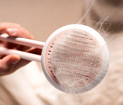 Pet grooming brush with collected fur on a neutral background