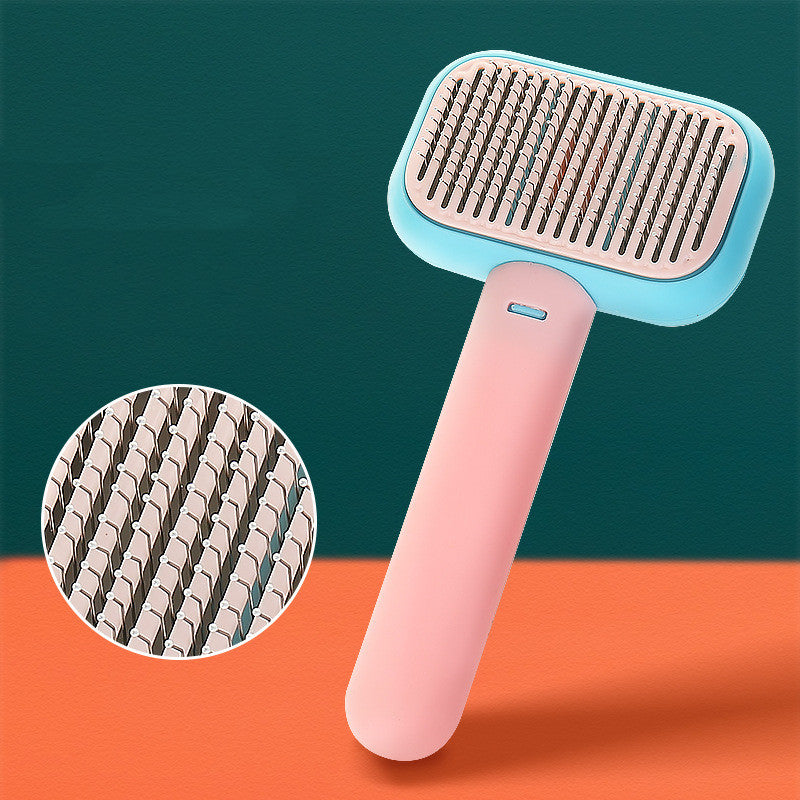 Pet grooming brush with pink handle and blue top on a green and orange background