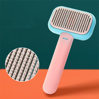 Pet grooming brush with pink handle and blue top on a green and orange background