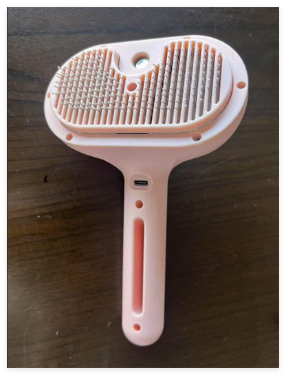 Pink pet grooming brush on a dark surface
