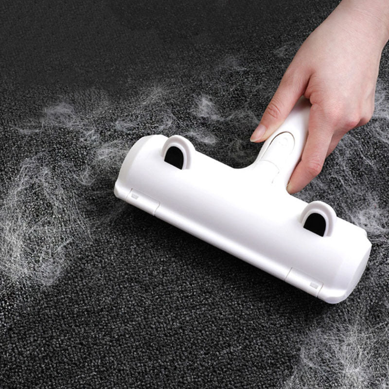 Hand using a white squeegee on a dark surface with water droplets.